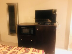 A dark wooden cabinet with a microwave and a flat-screen TV on top.