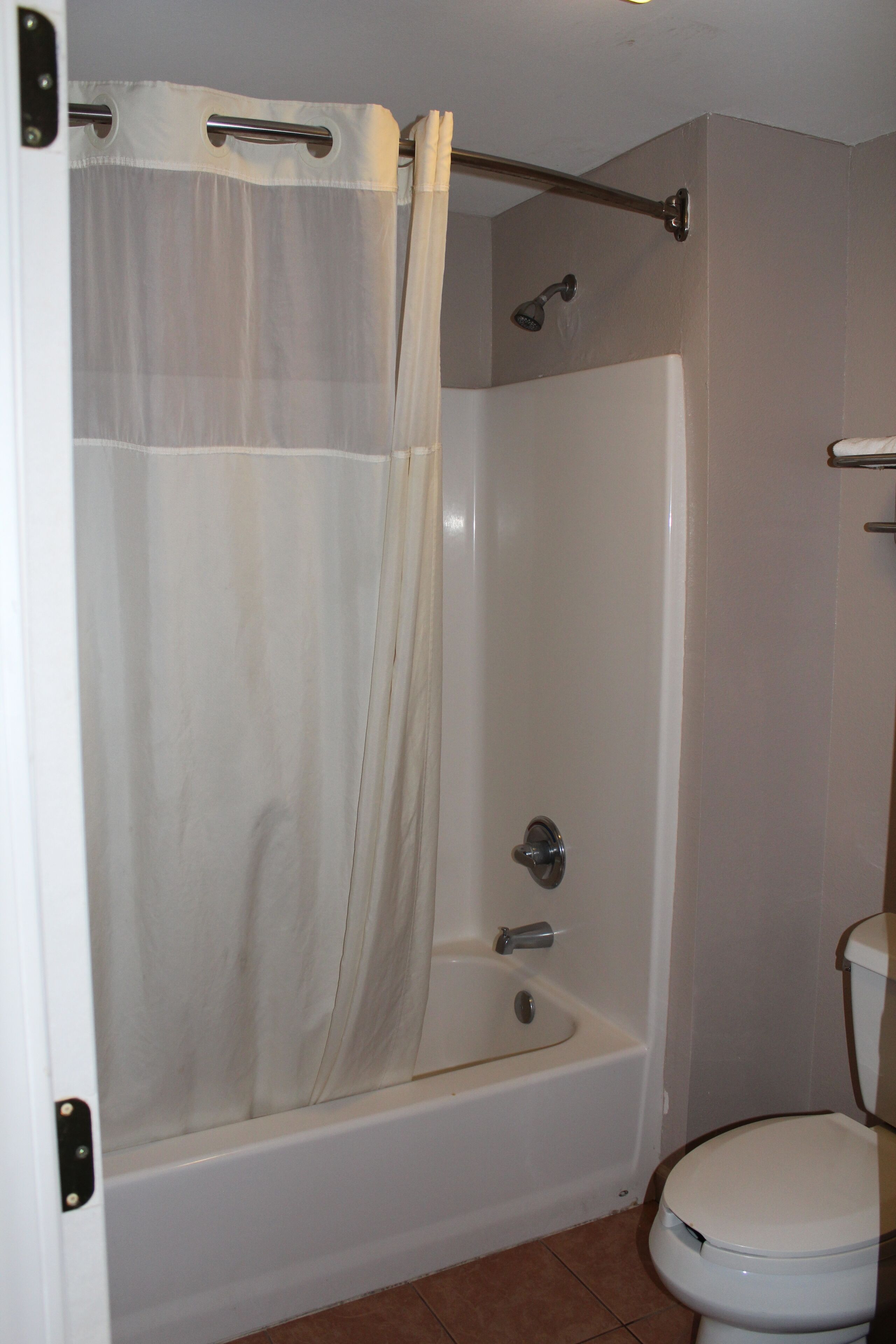 A bathroom with a bathtub, toilet, and shower curtain.