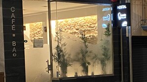 Entrada de un hotel con puerta de vidrio, un letrero que dice 'Café Bad' y un letrero de neón que anuncia 'Hostal'.