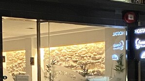 Entrada de un hotel con puerta de vidrio, pared interior de piedra y un letrero que dice "HOSTAL".