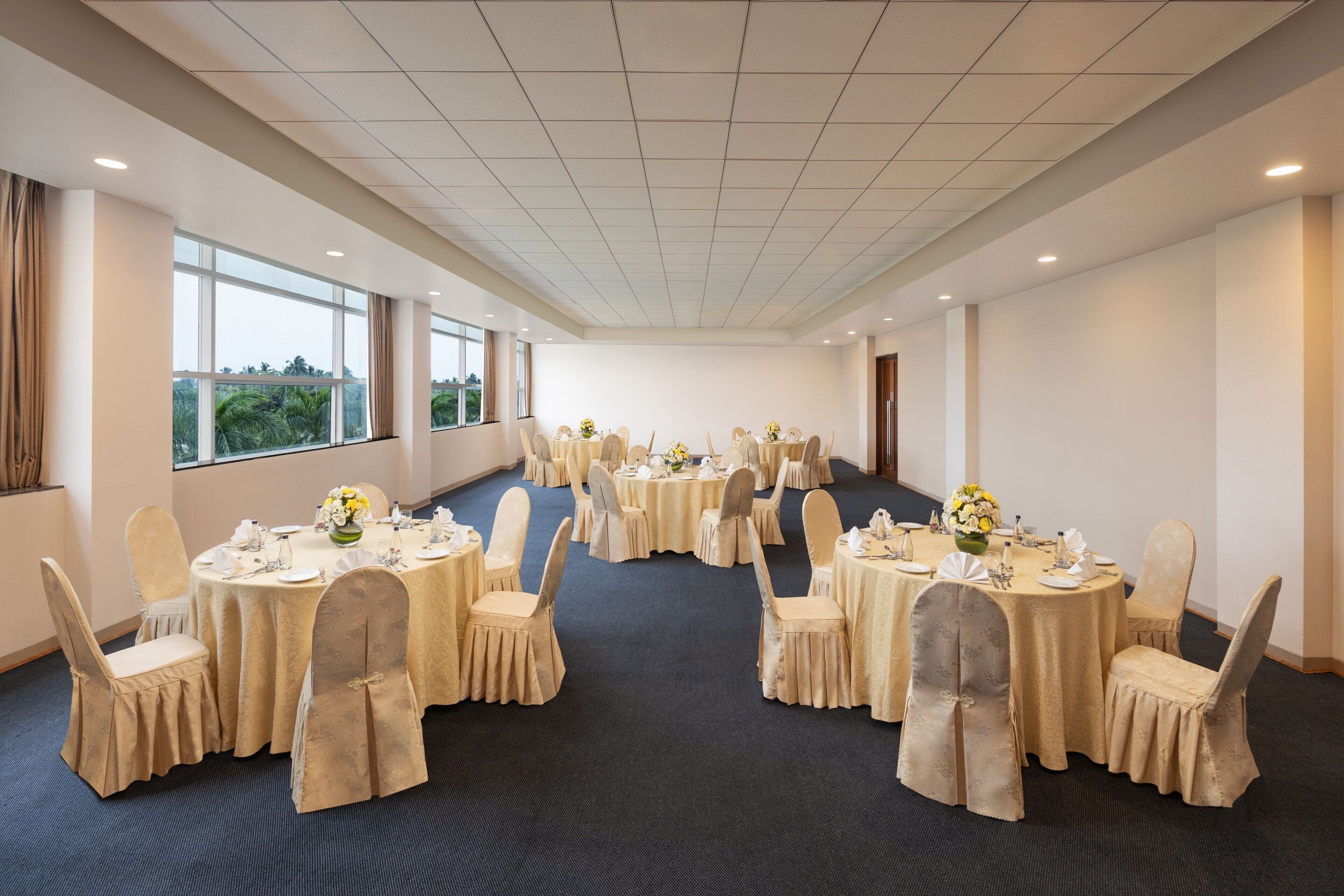 A conference room with multiple round tables, each set with chairs and centerpieces.