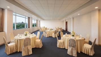 Un salón de conferencias con varias mesas redondas, cada una dispuesta con sillas y centros de mesa.