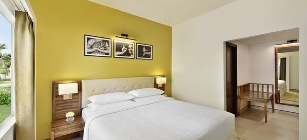 Una habitación de hotel con una cama, lámparas de noche, una mesita de noche y un espejo.