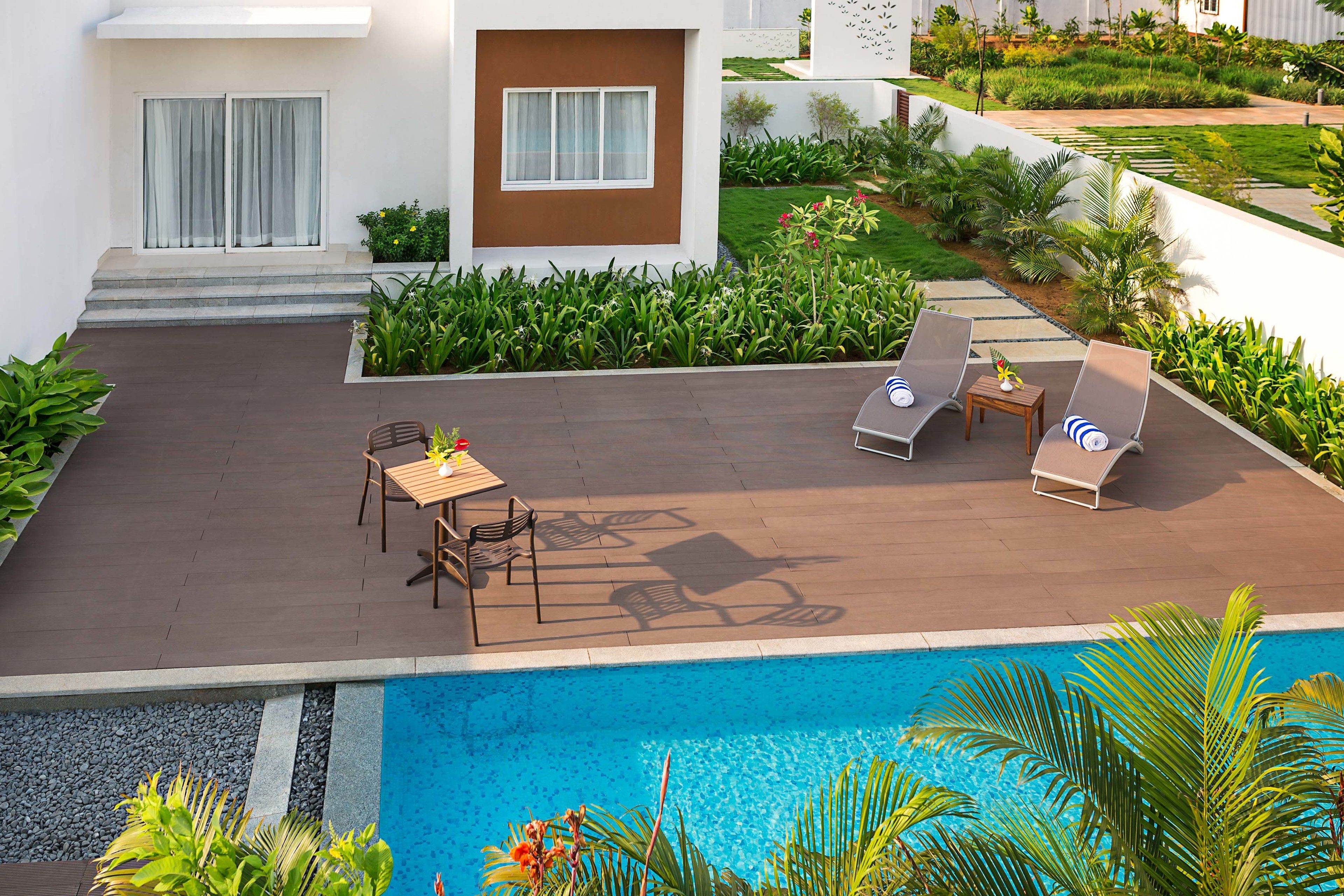 A poolside area with lounge chairs, a table, and a small garden.