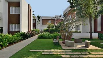A modern building with a well-maintained lawn, outdoor seating, and a variety of plants.