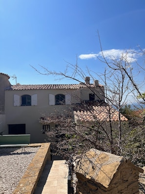 A building with a tiled roof, a stone wall, and a gravel path.