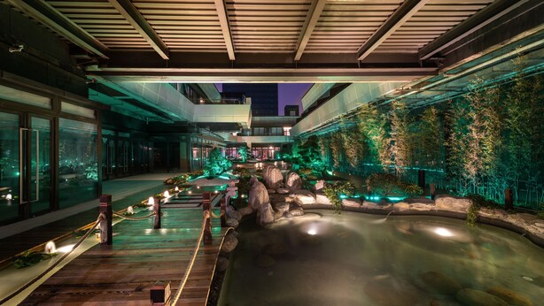 Un jardín interior tranquilo con estanque de carpas, terraza de madera y plantas de bambú.