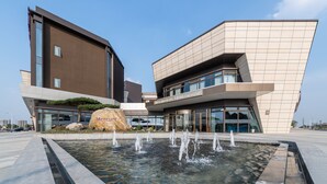 Un hotel moderno con un diseño arquitectónico único, que presenta una gran roca como elemento central y una fuente de agua en primer plano.