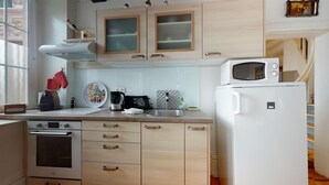 A kitchen with wooden cabinets, a microwave, a stove, and a sink.