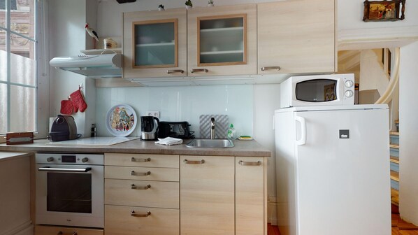 Una cocina con gabinetes de madera, microondas, estufa y pileta.