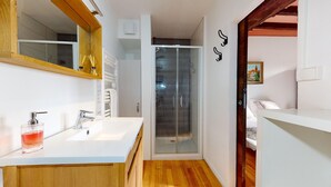 A modern bathroom with a shower, a sink, and a mirror.