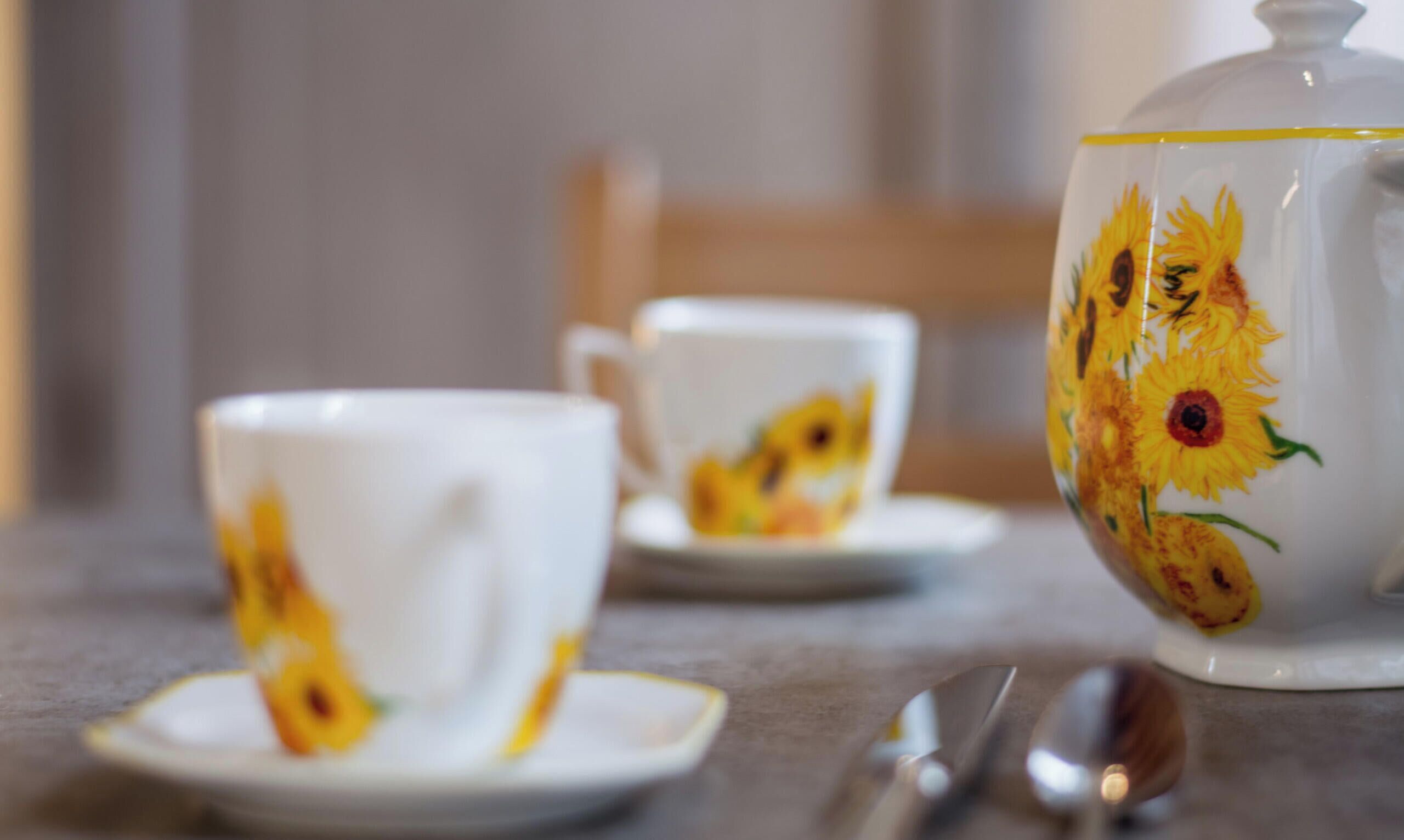 Een tafel met een theepot en twee kopjes met bloemmotieven.
