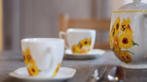 A table with a teapot and two cups with floral designs.