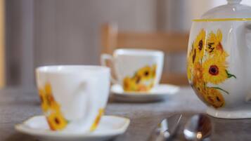 A table with a teapot and two cups with floral designs.