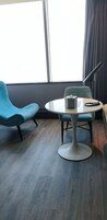 A modern room with a round table, two blue chairs, a tissue box, and a remote control.