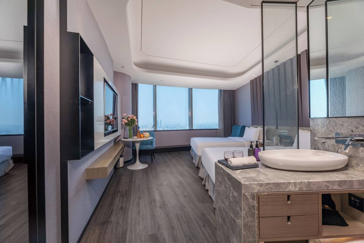 Habitació d'hotel moderna amb un llit gran, un escriptori, un lavabo rodó i vista a la ciutat.