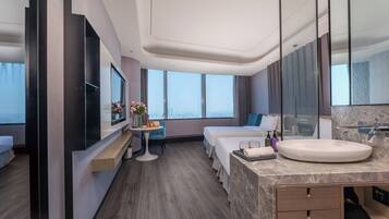 Habitación de hotel moderna con una cama grande, un escritorio, un lavamanos redondo y vistas a la ciudad.
