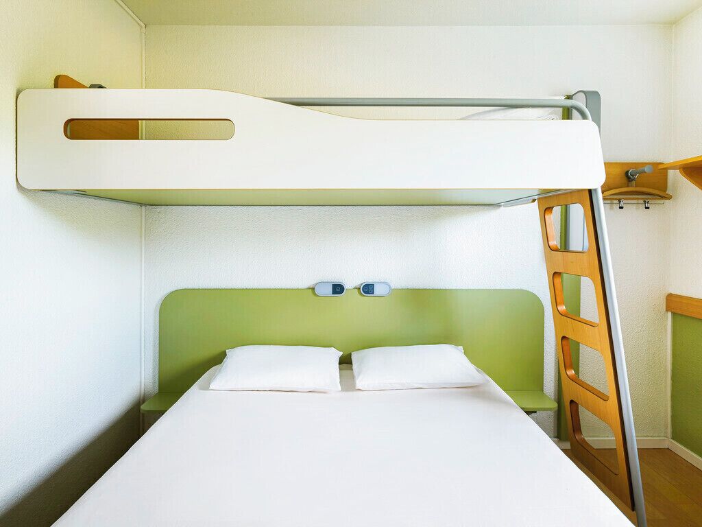 A bunk bed with a green headboard and white bedding.
