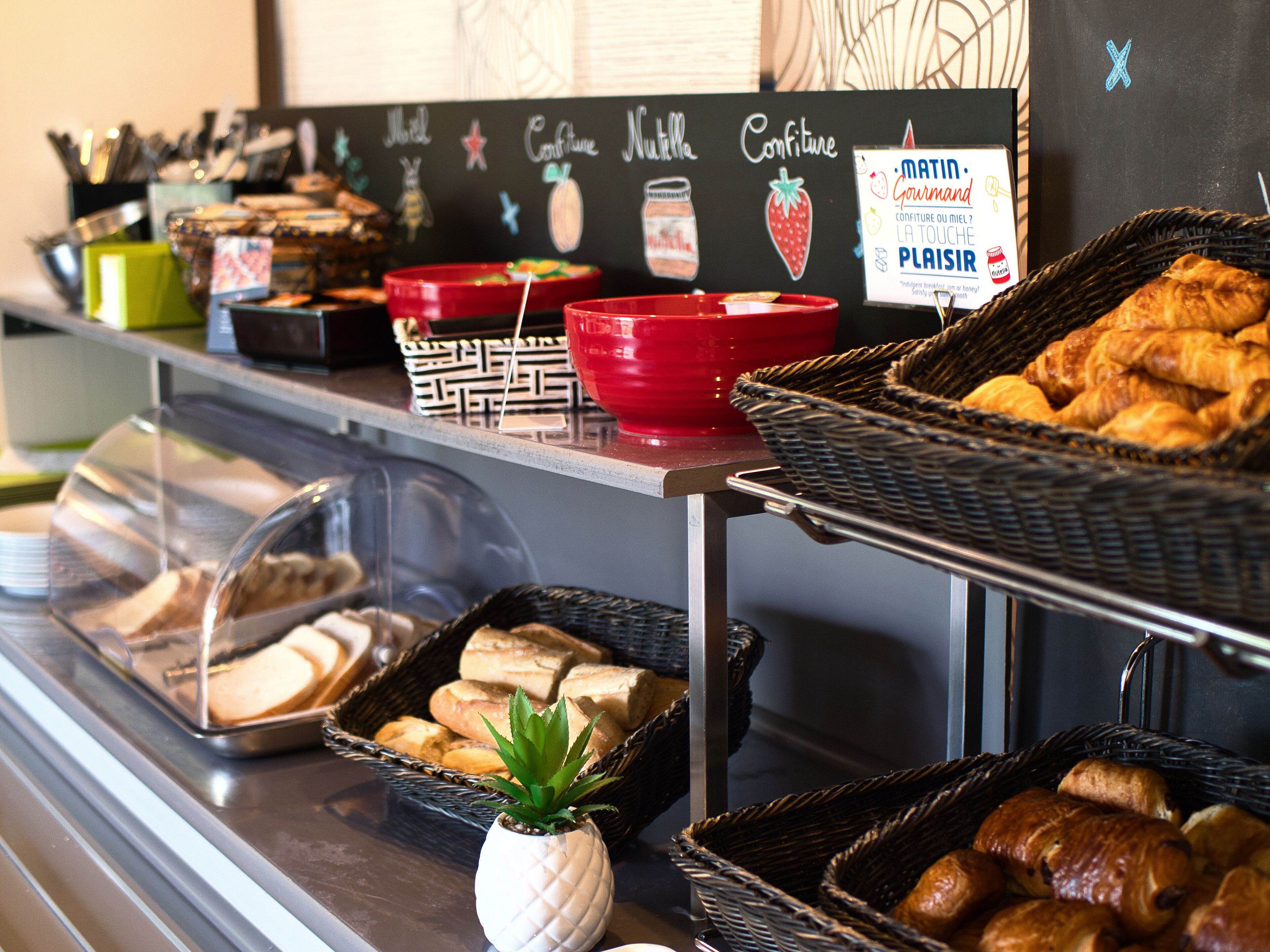 Une vitrine de boulangerie présentant diverses pâtisseries et une pancarte faisant la publicité de produits de qualité supérieure.