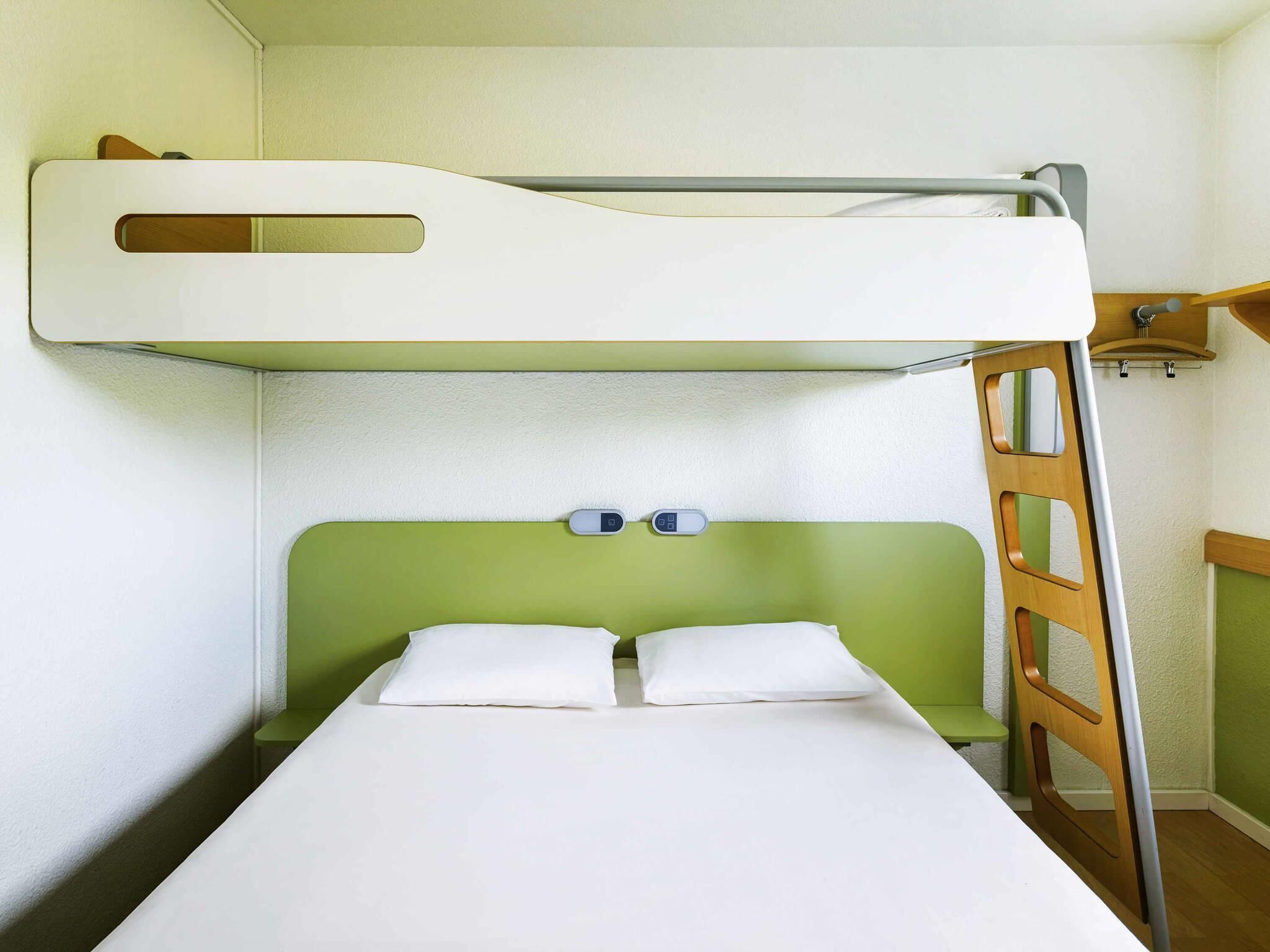 Un letto a castello con un poggiatesta verde, due cuscini e una scala.