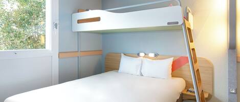 A bunk bed with a ladder, a bedside table, and a window with a view of trees.