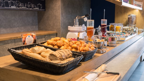 A buffet with croissants, bread, and a coffee machine. - ibis budget Rennes Route de Lorient (Rennes)