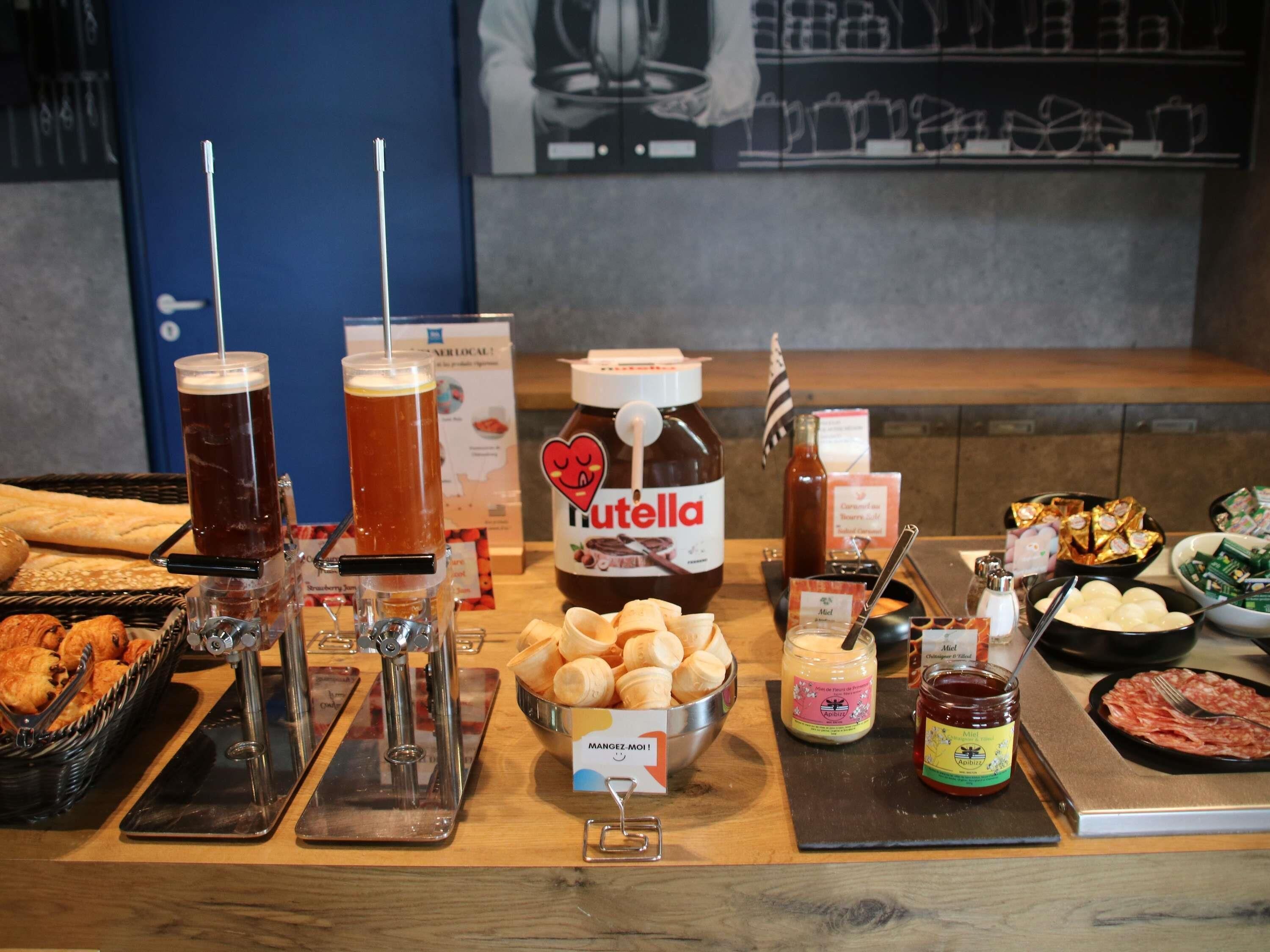 A buffet table with various food items, a jar of Nutella, and two beer taps.