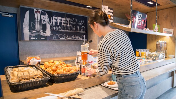 Balcão de buffet com diversos alimentos e um dispensador de bebidas.