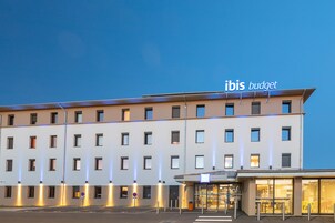 Un hôtel moderne, avec plusieurs étages, une entrée couverte et des fenêtres illuminées.
