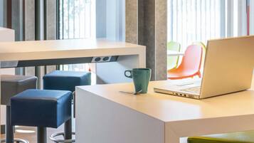 Een moderne werkplek met een laptop, een groene mok en een wit bureau.