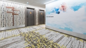 Ein Hotelgang mit Holzboden, einer Wand mit Berggelände- und Himmelgemälde und einem Schild mit Text.