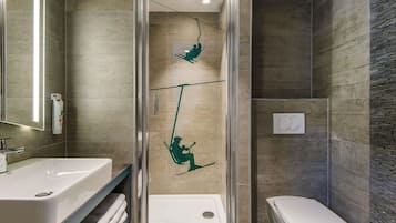 Un baño moderno con cabina de ducha de vidrio, un lavamanos blanco y un inodoro.