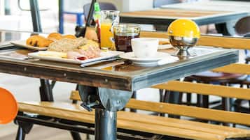 Una mesa de desayuno con diversos alimentos, una taza de café y un vaso de jugo.