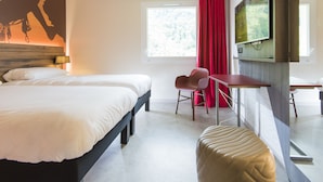 Ein modernes Hotelzimmer mit einem großen Bett, einem Schreibtisch, einem Stuhl und einem an der Wand befestigten Fernseher.