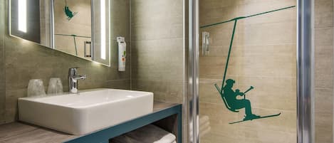 Un baño con lavamanos, espejo, toallero y cabina de ducha de vidrio.