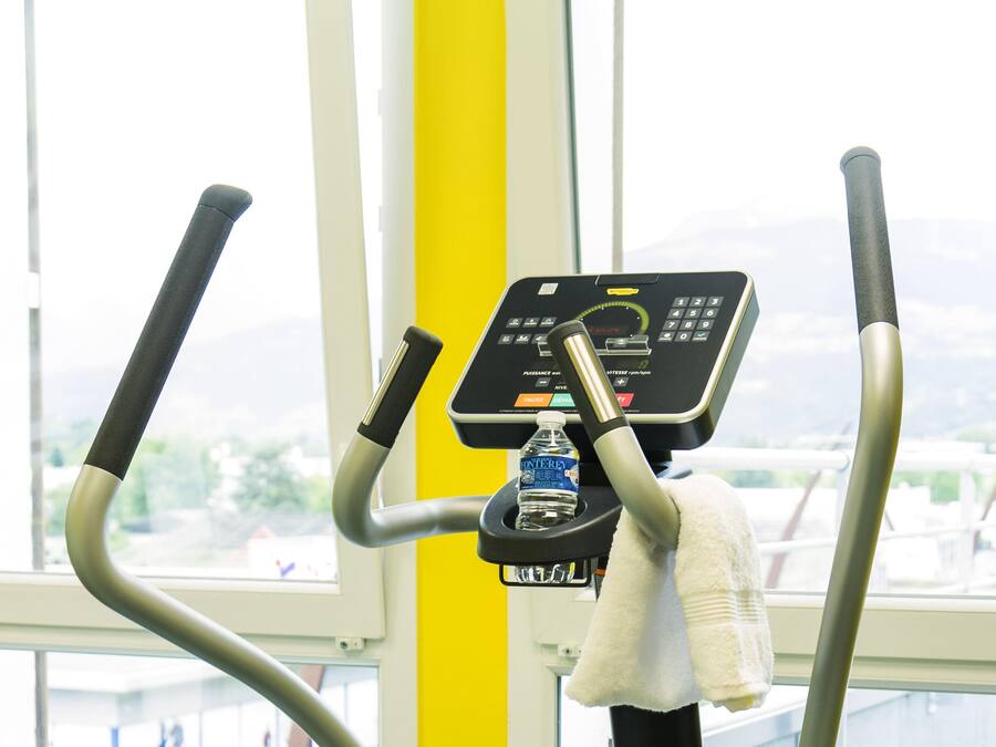 A stationary exercise bike with a digital display, a water bottle, and a towel.