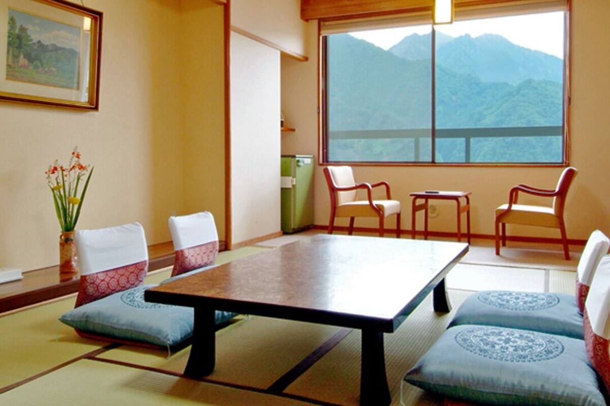 Ein traditioneller japanischer Raum mit Tatami-Boden, einem niedrigen Tisch und Kissen.