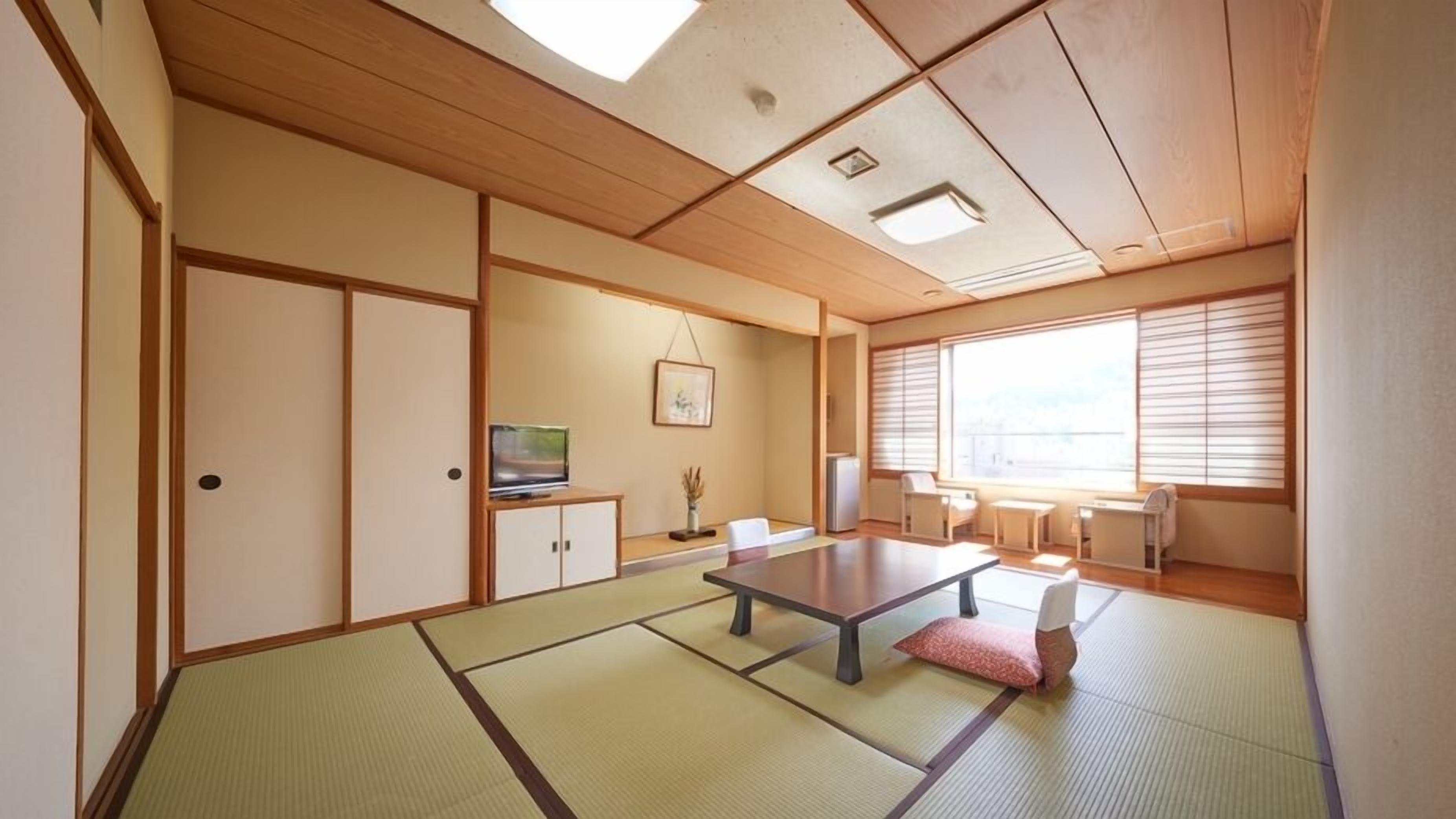 Una habitació japonesa tradicional amb sòcols de tatami, una taula baixa, portes corredisses i una finestra gran.
