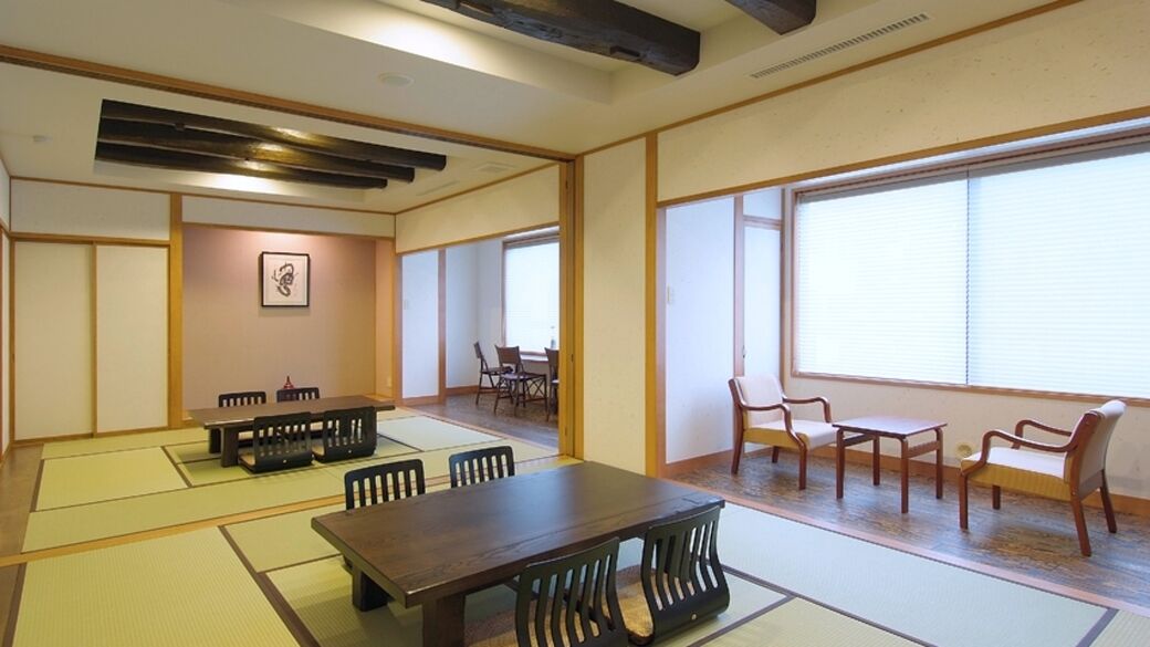 Una habitació tradicional japonesa amb sòls de tatami, taula de fusta, cadires i grans finestres.