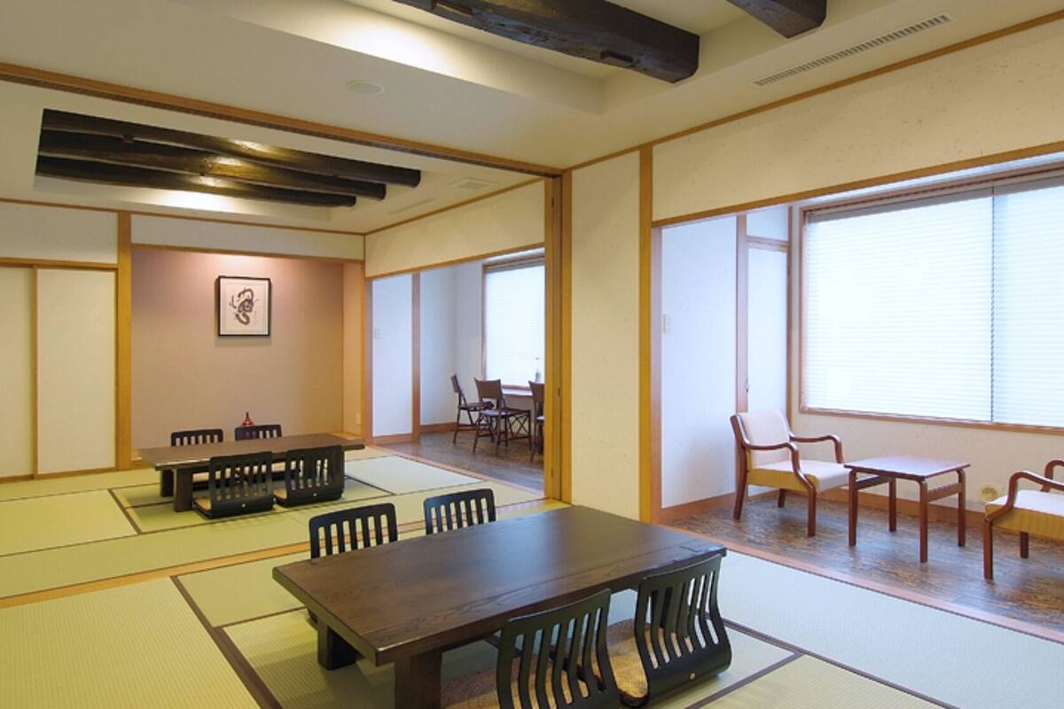 Una habitación japonesa tradicional con suelo de tatami, una mesa baja con sillas y puertas correderas.