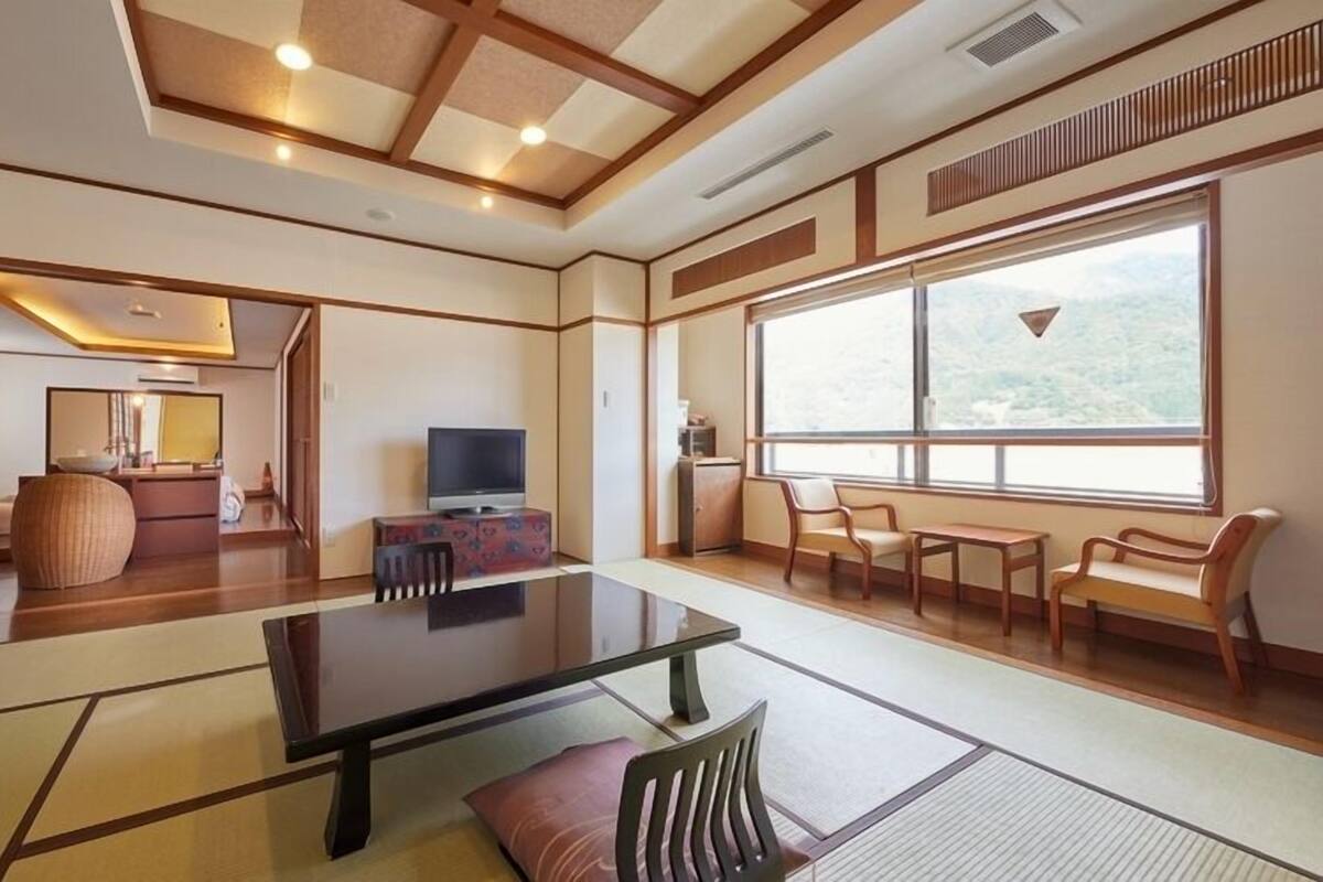 Una habitación tradicional japonesa con suelo de tatami, una mesa baja y puertas correderas.