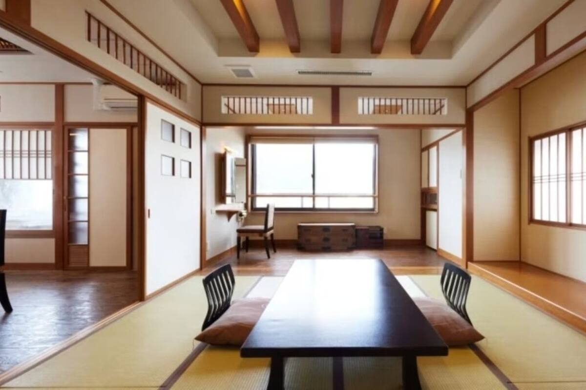 Una habitación tradicional japonesa con suelo de tatami, una mesa baja y puertas correderas.