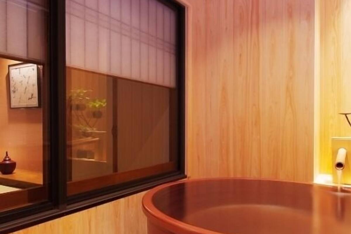 Ein modernes Badezimmer mit einer großen Holzwanne, einem kleinen Waschbecken und einem Fenster mit Blick ins Freie.