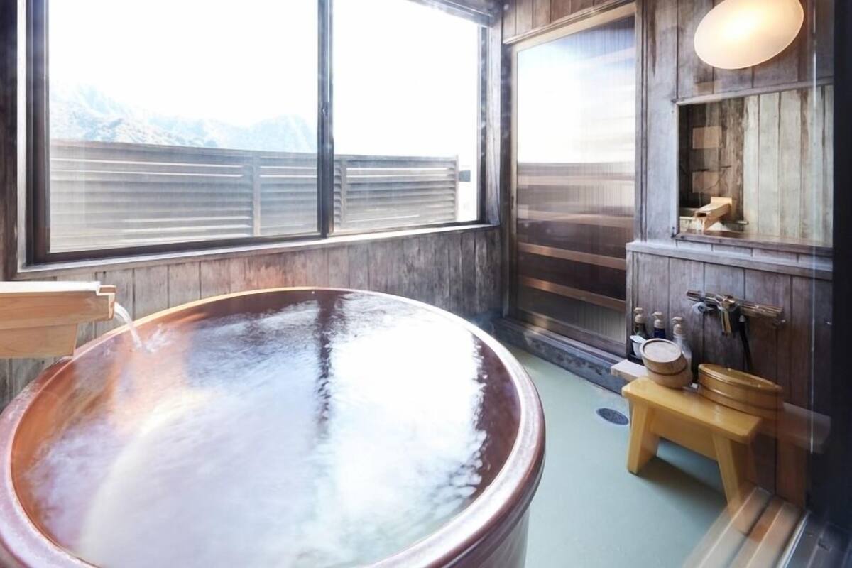 Un jacuzzi con interior de madera, una ventana y un banco de madera.