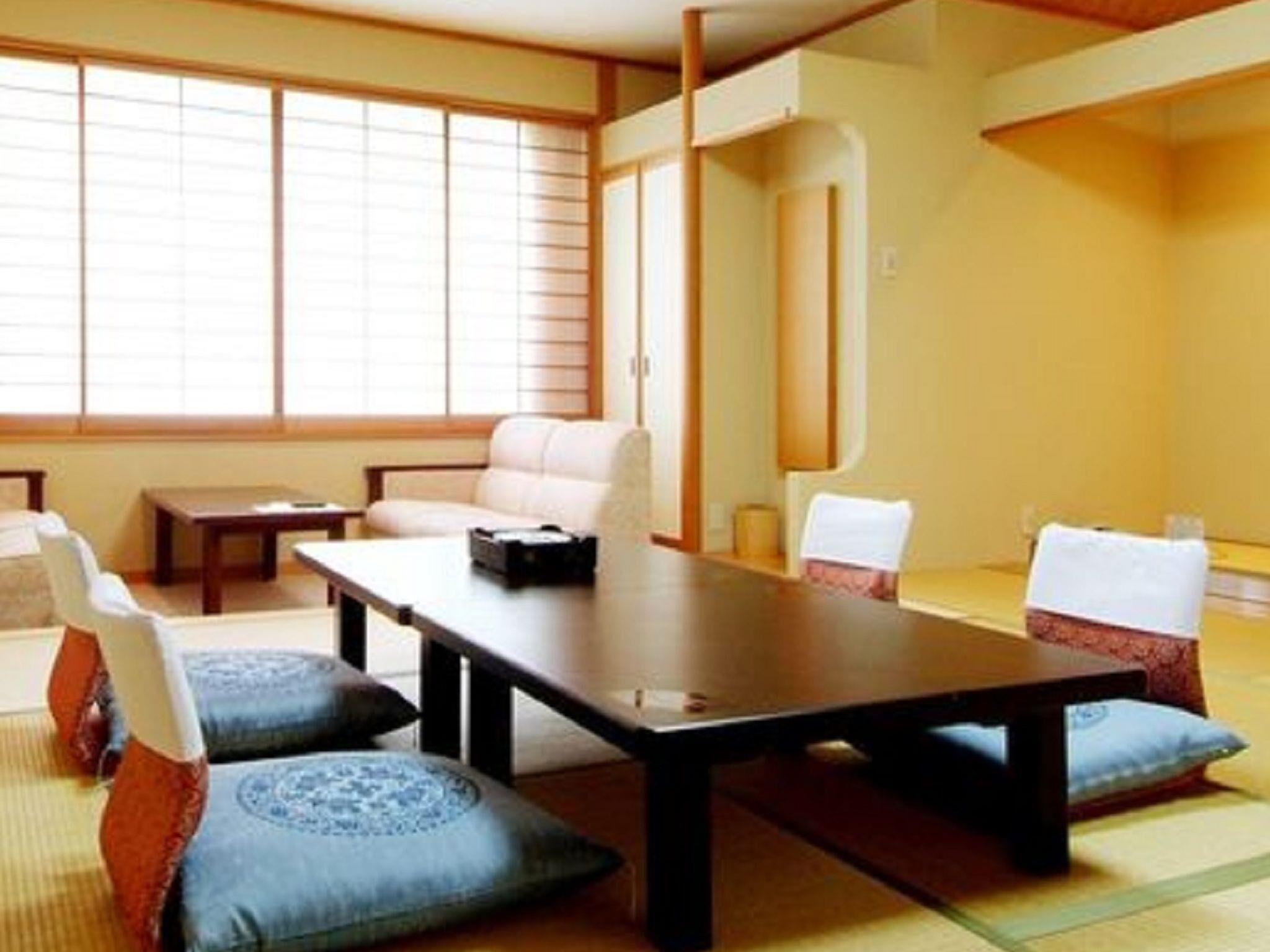 Una habitación japonesa tradicional con suelo de tatami, una mesa baja y un sofá.