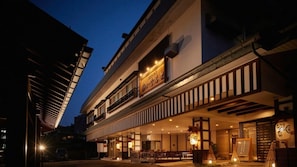 A two-story building with a restaurant on the ground floor, featuring a covered outdoor seating area and traditional Japanese decor.
