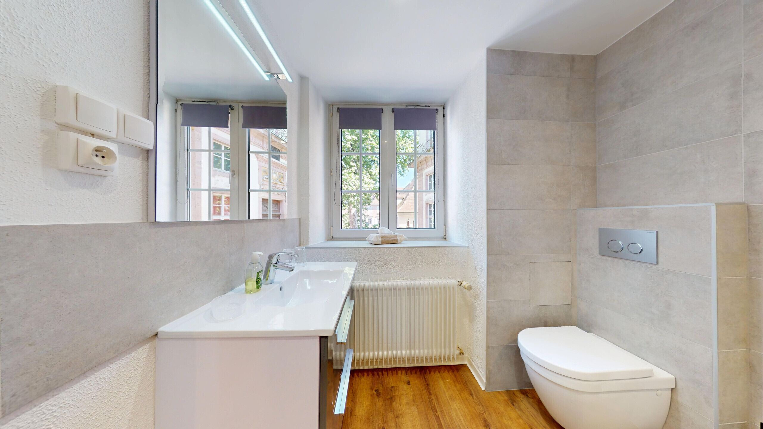 A modern bathroom with a white sink, mirror, and toilet.