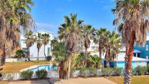 Et resort med pool, palmer og bygninger ud til stranden.