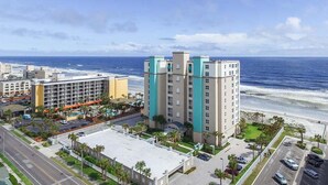 Et kysthotel med flere bygninger, parkeringsplads og udsigt til stranden.