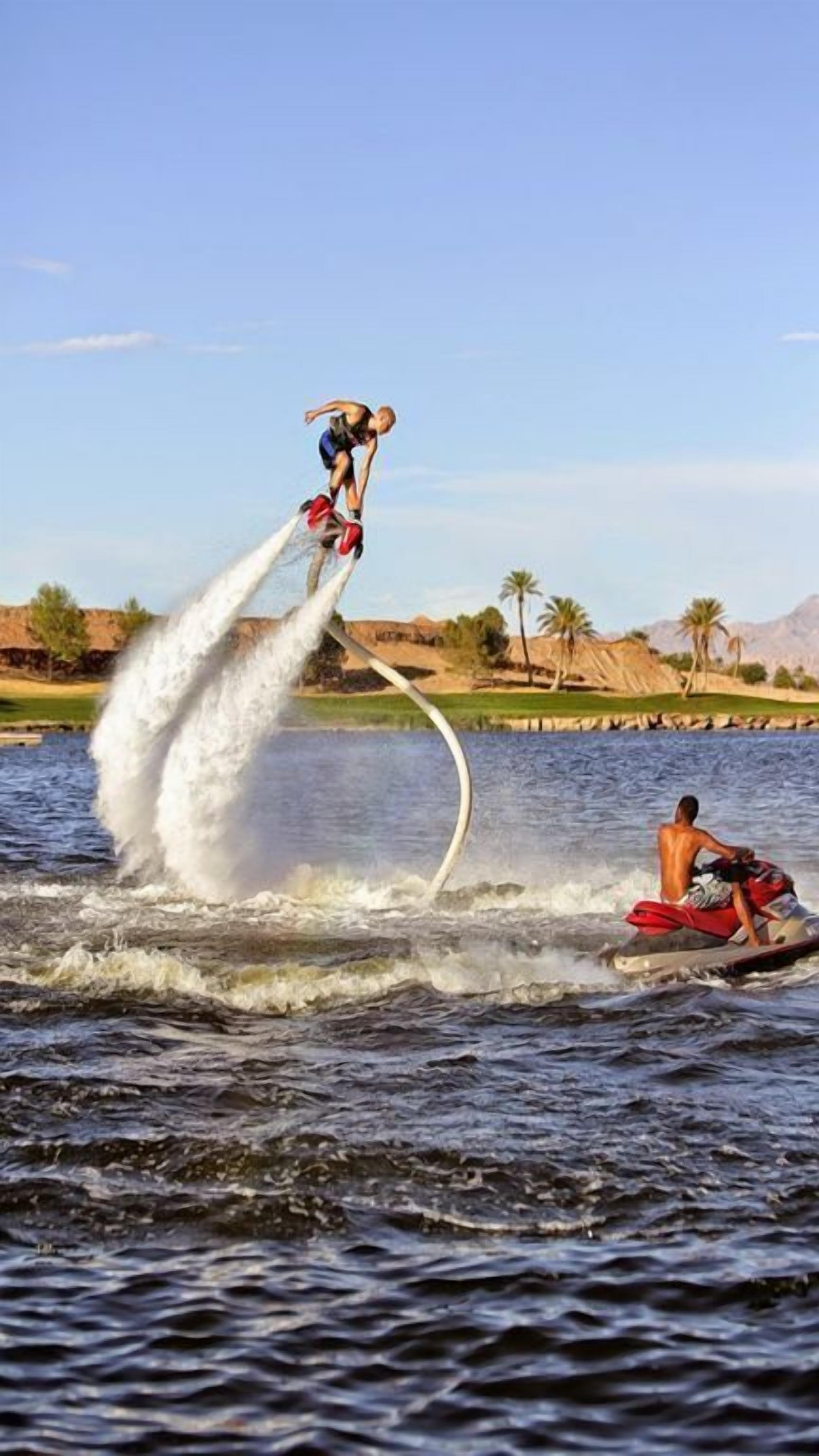 A person wakeboarding over water with a wakeboard and a wakeboarder in a boat.